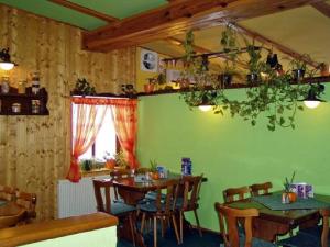 ein Esszimmer mit Holztischen und einer grünen Wand in der Unterkunft Restaurace a Penzion u Vladaru in Mikulášovice