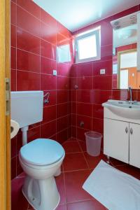 La salle de bains rouge est pourvue de toilettes et d'un lavabo. dans l'établissement Apartments by the sea Tkon, Pasman - 19913, à Tkon