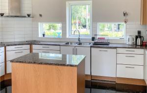 a kitchen with white cabinets and a sink and two windows at Beautiful Home In Tived With Wifi in Tived