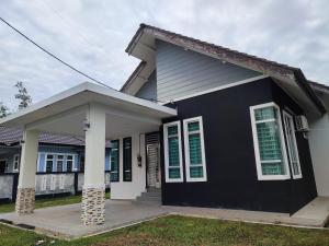 a black and white house with green shutters at Villa Tamu Dr Din - Pool OR Soopa Doopa in Rantau Panjang
