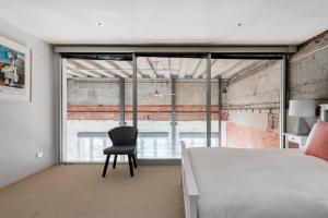 - une chambre avec un lit et une chaise en face d'une fenêtre dans l'établissement Luxury Warehouse Loft, à Melbourne