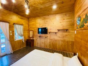 a bedroom in a log cabin with a bed and a tv at Berry Valley Homestay in Da Lat