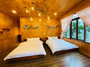 two beds in a room with wooden walls and windows at Berry Valley Homestay in Da Lat