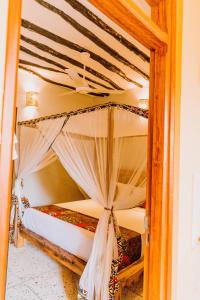 a bed with a canopy in a room at Mkunguni Villas in Bwejuu