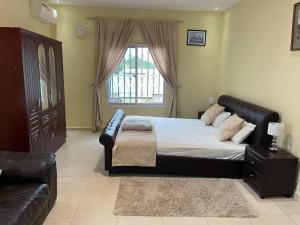 1 dormitorio con cama, sofá y ventana en Janha's Senegambia Villa Holiday Rental With Free Wifi, en Amdalai