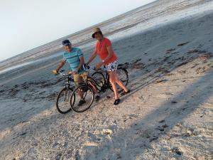 two men standing with their bikes on the beach at Barry's Beach Resort in Mkwaja