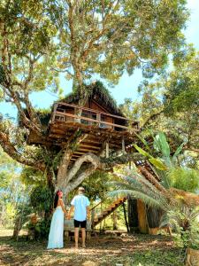 a bride and groom standing in front of a tree house at Art Jungle Eco Lodge in Itacaré