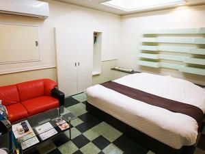 Yoshioka的住宿－メルヘンの森パート2大人専用，一间卧室配有一张床和一张红色的沙发