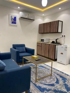 دانة الفخامه للشقق الخدومة في تبوك: غرفة معيشة مع كرسيين ازرق وطاولة قهوة