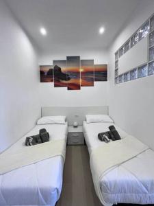 2 camas en una habitación blanca con pinturas en la pared en Casa 'da Annunziata' few steps from the sea, en Pizzo