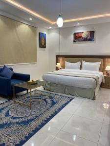 - une chambre avec un grand lit et un canapé bleu dans l'établissement دانة الفخامه للشقق الخدومة, à Tabuk