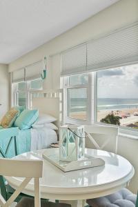 Beach Views by Day , Star Gazing by Night - Hawaiian Inn Beach Resort في Daytona Beach Shores: غرفة نوم بسرير وطاولة وإطلالة على الشاطئ
