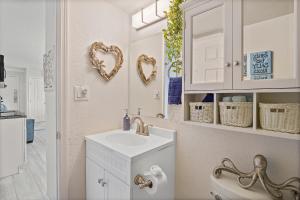 a white bathroom with a sink and a mirror at Beach Views by Day , Star Gazing by Night - Hawaiian Inn Beach Resort in Daytona Beach Shores