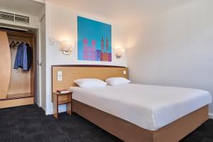 a bedroom with a large bed and a blue painting on the wall at Kyriad Direct Strasbourg Ouest - Zénith in Strasbourg