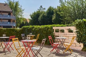 - un ensemble de tables et de chaises dans un jardin dans l'établissement Kyriad Direct Strasbourg Ouest - Zénith, à Strasbourg