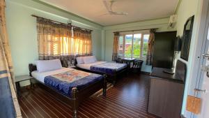 um quarto com 2 camas e uma televisão de ecrã plano em Nanohana Lodge em Pokhara