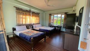 a room with two beds and a flat screen tv at Nanohana Lodge in Pokhara