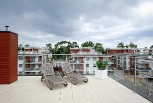 2 sillas en la parte superior de un balcón con edificios en Apartament Golden View - Rewal Morska 1 en Rewal