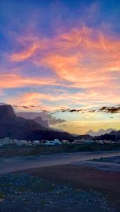 una puesta de sol en el desierto con montañas en el fondo en 228Hostel, en Al Ḩamrāʼ