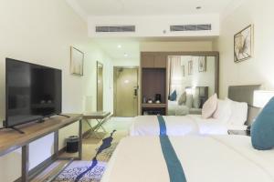 a hotel room with two beds and a flat screen tv at Safwat Alkhobar Hotel in Al Khobar
