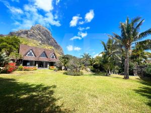a house on a lawn with a mountain in the background at Villa Ayapana in Le Morne