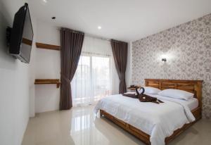 a bedroom with a bed and a flat screen tv at Central Inn Senggigi in Senggigi