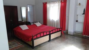 博尔普尔Nibhriti Guest House的一间卧室配有红色的床和红色窗帘 更多5张照片