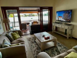 een woonkamer met een bank en een flatscreen-tv bij Grand Baie Beach Penthouse in Grand Baie