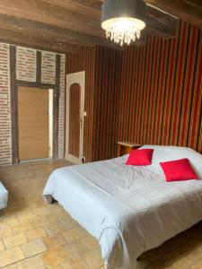 - une chambre avec un grand lit blanc et des oreillers rouges dans l'établissement La Grange d Ave, à Luynes