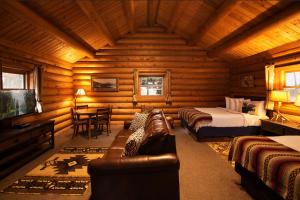 Dormitorio en cabaña de madera con cama y sofá en Lochsa Lodge en Lolo