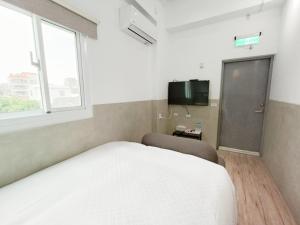 - une chambre avec un lit blanc et une télévision dans l'établissement No 9 Hotel-九號文旅, à Tainan