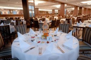 un comedor con mesas y sillas blancas en ALUSSO THERMAL HOTEL SPA en Afyon