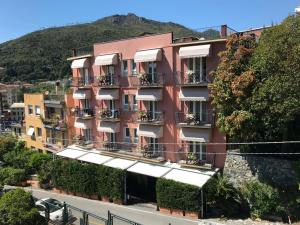 a pink building with white awnings on a street at Hotel Carla in Levanto