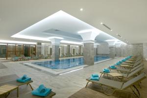 ein Pool in einem Hotel mit Stühlen und einem Pool in der Unterkunft ALUSSO THERMAL HOTEL SPA in Afyonkarahisar