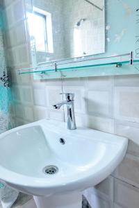 a white sink in a bathroom with a mirror at Indigo cottage and Apartment in Kumasi