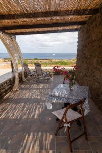 patio ze stołem i krzesłami oraz oceanem w obiekcie Dammusu di Turì w mieście Pantelleria