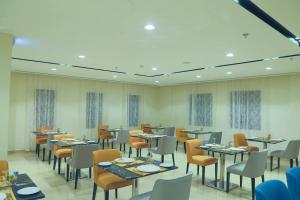 uma sala de jantar com mesas e cadeiras num restaurante em Safwat Alkhobar Hotel em Al Khobar