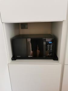 a black microwave in a white cabinet in a kitchen at Maison Gabrielle in Verona