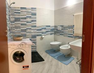 ein Badezimmer mit einer Waschmaschine und einem WC in der Unterkunft LOCAZIONE TURISTICA "RI-ALE" a DUE PASSI DAL MARE BARI SARDO - OGLIASTRA - COD IUN Q8596 in Bari Sardo
