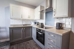 a kitchen with white cabinets and a sink and a stove at Beautiful 4 Berth Seaside Apartment In Great Yarmouth, Norfolk Ref 99006s in Great Yarmouth