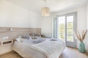 a white bedroom with a bed and a window at Nidam in Bilieu