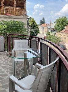 a glass table and two chairs on a balcony at GS Hotel in Tbilisi City