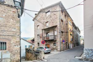 an old stone building with a car parked in a street at Can MartiPol in La Pobla de Lillet