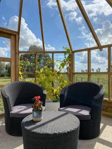 dos sillas y una mesa con un jarrón de flores en un porche en Sunbjerre B&B en Lille Dalby