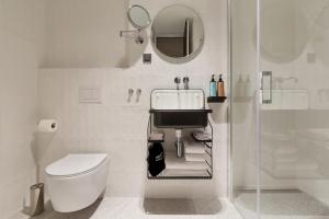 Baño blanco con aseo y espejo en Bona Fide Main Square Designer Apartments, en Zagreb