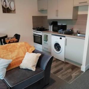 a kitchen with a couch and a washing machine in it at Carvetii - Norman House - 2nd floor, 1 bedroom flat in Boʼness