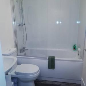 y baño blanco con aseo y ducha. en Carvetii - Norman House - 2nd floor, 1 bedroom flat en Boʼness