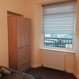 1 dormitorio con vestidor y ventana con persiana en Carvetii - Norman House - 2nd floor, 1 bedroom flat en Boʼness