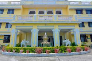 Saipur的住宿－Singrauli Palace Heritage Hotel，一座黄色的建筑,前面有一个喷泉