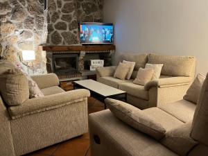 sala de estar con 3 sofás y chimenea en La Casita de las Hortensias, en Ortigosa del Monte
